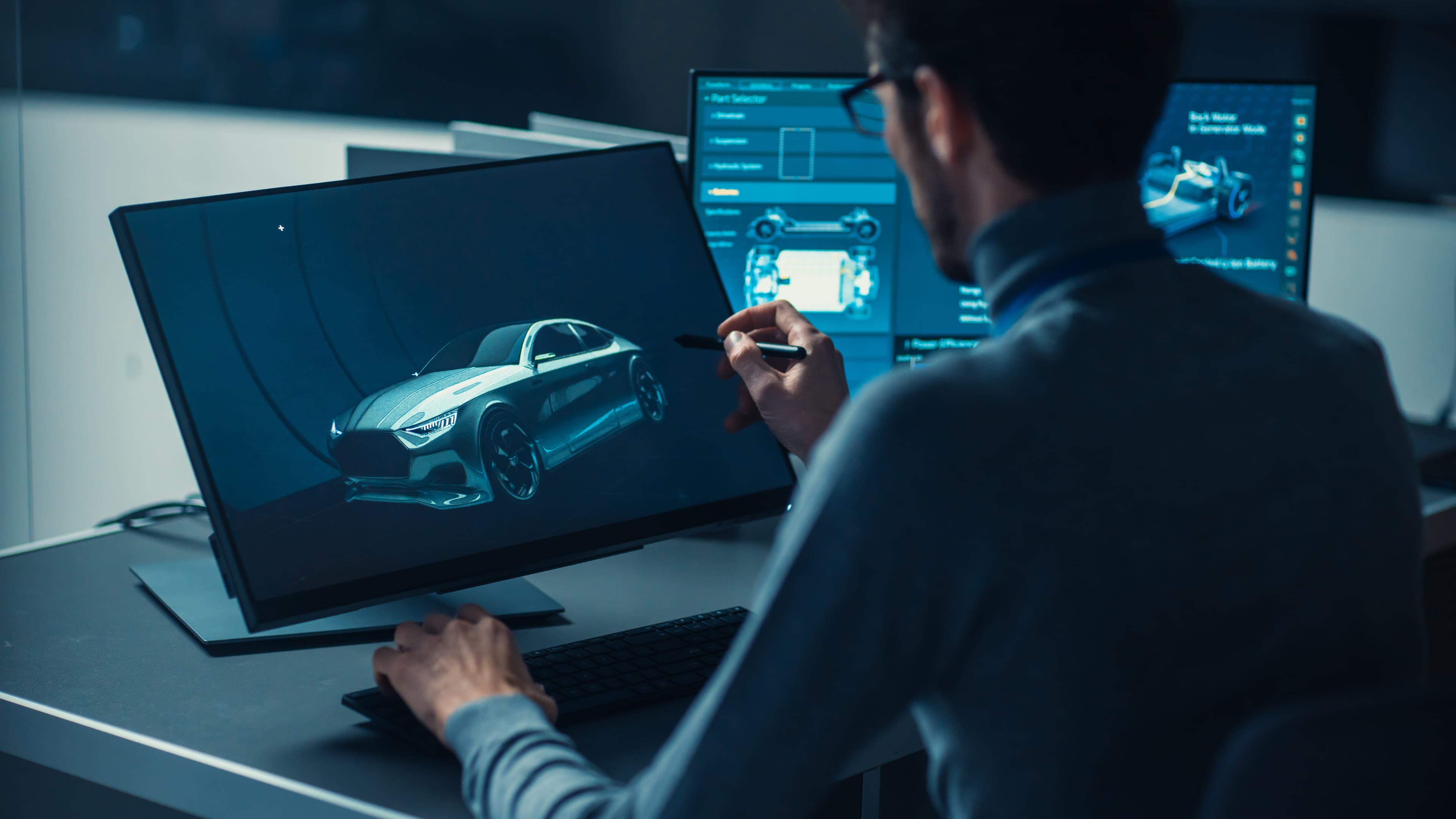 Automotive designer reviewing advanced vehicle technology on digital screens